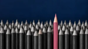 Lápis alinhados com um lápis rosa em destaque ilustram diferenciação de marca e o conceito de mesmice
