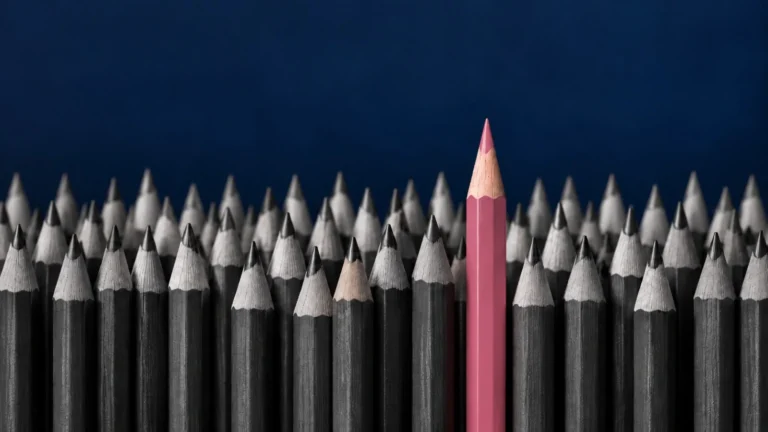 Lápis alinhados com um lápis rosa em destaque ilustram diferenciação de marca e o conceito de mesmice